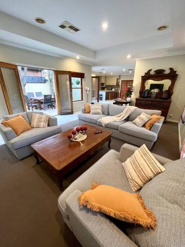 a living room with couches and a coffee table at Grand retreat in town in Albury