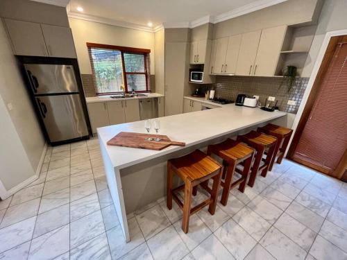 a kitchen with a large white island with wooden chairs at Grand retreat in town in Albury