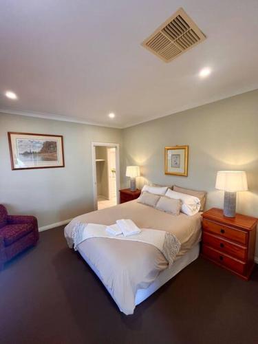 a bedroom with a large bed and a chair at Grand retreat in town in Albury