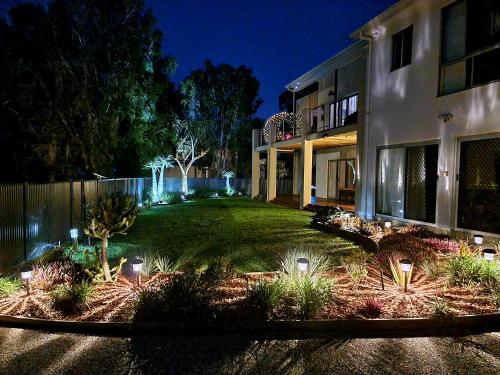 a house with lights in a yard at night at Seaside holiday house in Burrum Heads