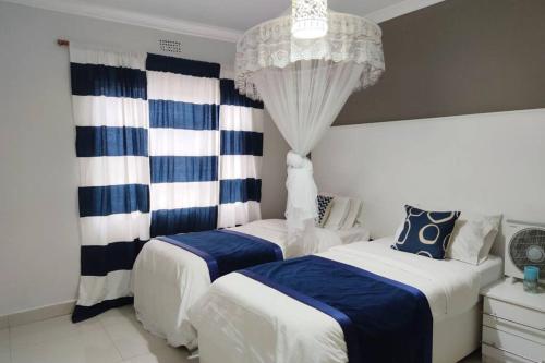 1 dormitorio con 2 camas y lámpara de araña en Nichi's Guesthouse - Cosy 3 bedroom with breakfast en Blantyre