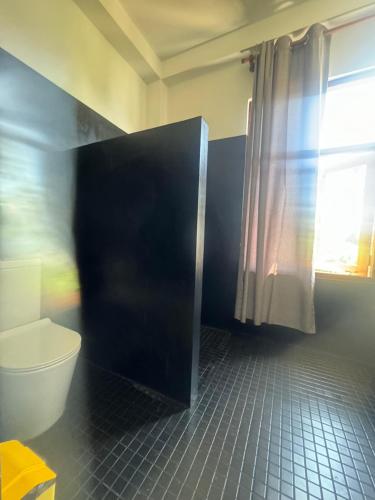 a bathroom with a toilet and a window at Coconut Palm beach restaurant and rooms in Dickwella