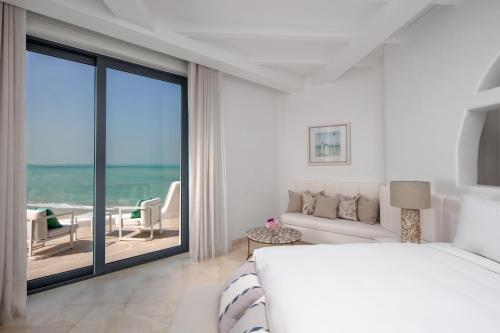 um quarto com uma cama e vista para o oceano em Anantara Santorini Abu Dhabi Retreat-Adults Only em Al Rahba