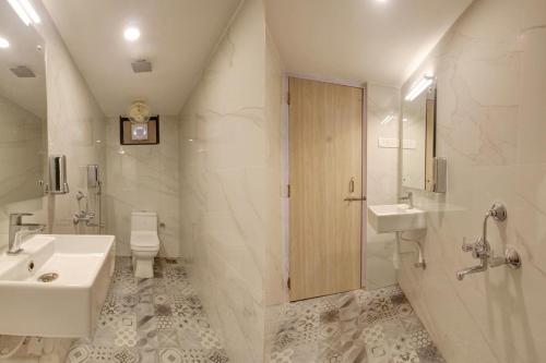 a white bathroom with a sink and a toilet at Rahul Service Apartment in Calangute