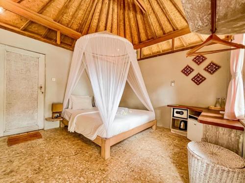 1 dormitorio con 1 cama con mosquitera en BUNGALOW CAFE GILI BEACH FRONT en Gili Meno