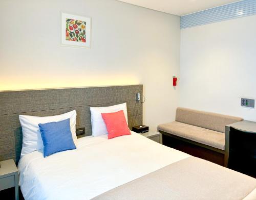 a hotel room with a bed with colorful pillows at Airsky Hotel Incheon in Incheon