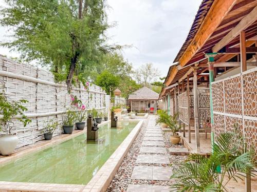 a garden with a pool of water and plants at Bungalow Cafe Gili Beachfront in Gili Meno