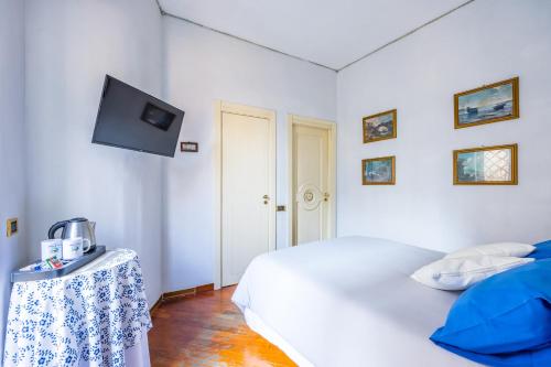 een witte slaapkamer met een bed en een tv aan de muur bij La Casa Di Bruno Napoli in Napels