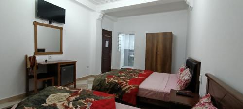 a bedroom with two beds and a television in it at Aramca in Bab Ezzouar