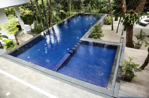 a large pool with blue water in a backyard at Hotel Lepic in Abidjan