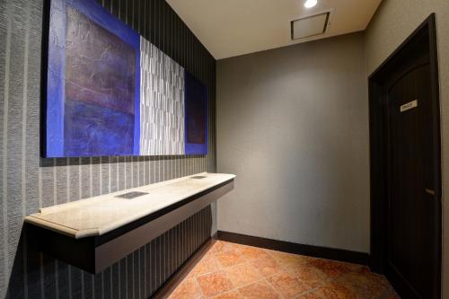 a bathroom with a sink and a painting on the wall at Hofu Grand Hotel in Hofu