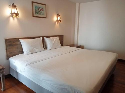 a bedroom with a large white bed with two lights at Sripat Guesthouse SHA Extra Plus in Chiang Mai