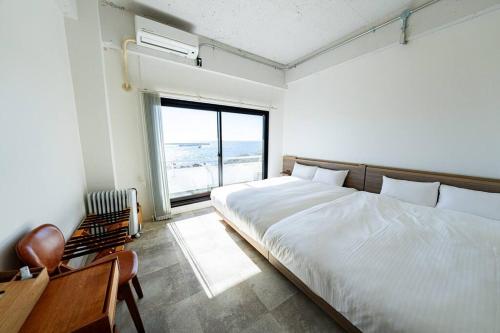 Un dormitorio con una cama y un escritorio y una ventana. en Moroisoso モロイソソウ 大型温水プール付 高級貸切ヴィラ BBQ＆プライベートビーチ, en Miura