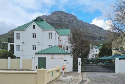 a white building with a mountain in the background at 31 Riverview in Cape Town