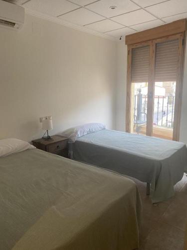 two beds in a room with a window at Ca' La Conchin in Cortez de Pallas