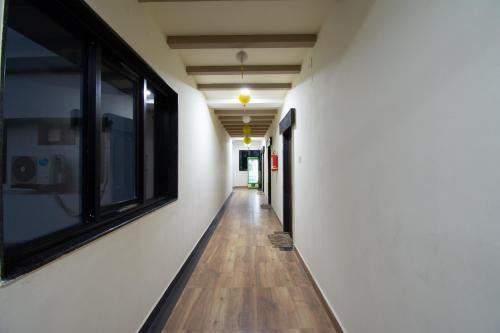 a hallway with white walls and wooden floors and a window at The Apsara in Rājahmundry