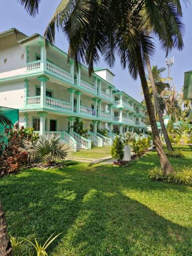 a large building with palm trees in front of it at D7 La Serene in Benaulim