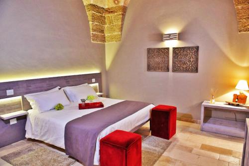 ein Schlafzimmer mit einem großen Bett und zwei roten Stühlen in der Unterkunft Masseria Elysium in Mesagne