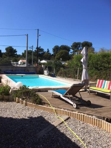- une piscine avec un fauteuil et un parasol dans l'établissement Joli pavillon individuel, à Carry-le-Rouet