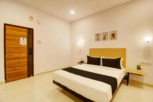 a bedroom with a large bed and a wooden door at Casa Grand Hotels Nacharam in Hyderabad