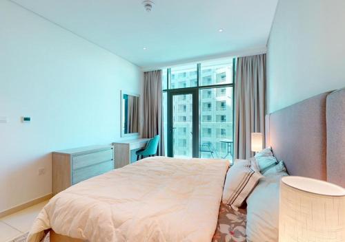 sypialnia z dużym łóżkiem i dużym oknem w obiekcie Beachfront Haven w Dubaju