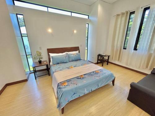 Schlafzimmer mit einem großen Bett mit blauer Bettwäsche und Fenstern in der Unterkunft Solitary Golf Home w/ Pool in Davao City
