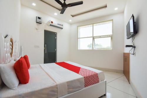 Schlafzimmer mit einem Bett mit roten Kissen und einem TV in der Unterkunft Hotel Shagun in Karnal