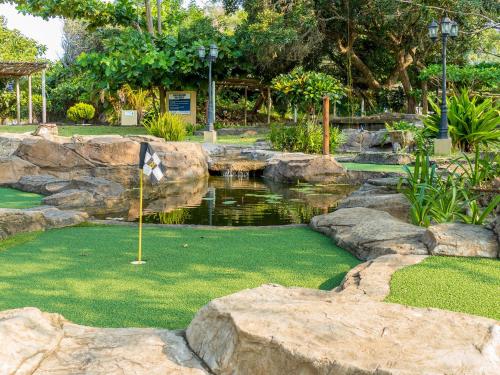 a golf course with a flag and a pond at San Martinho Beach Club in Vila Praia Do Bilene