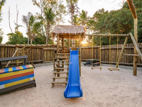 a playground with a blue slide and a swing at San Martinho Beach Club in Vila Praia Do Bilene
