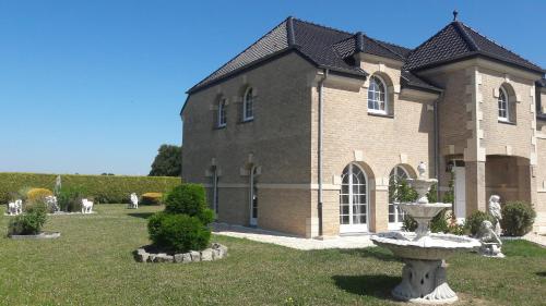ein großes Backsteingebäude mit einem Brunnen davor in der Unterkunft Maison d hôtes Salvatrice in Rouvroy