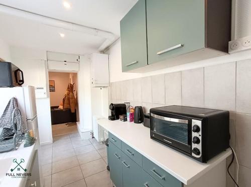 une cuisine avec un four micro-ondes au-dessus d'un comptoir dans l'établissement L'escabalt - jardin privé, à Nevers