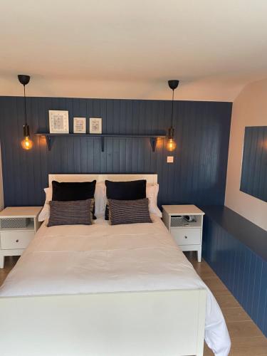 een slaapkamer met een groot wit bed en 2 tafels bij Hideaway Cottage in Schull