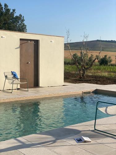 a swimming pool with a chair next to a building at Agriturismo Colle Igino in Matera