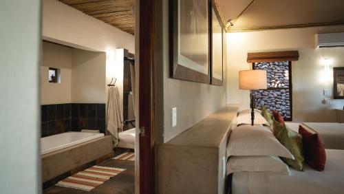 a bathroom with a tub and a bed and a sink at Mashatu Lodge in Lentswelemoriti