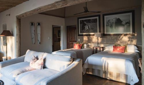 Cette chambre comprend deux lits et un canapé. dans l'établissement Mashatu Lodge, à Lentswelemoriti