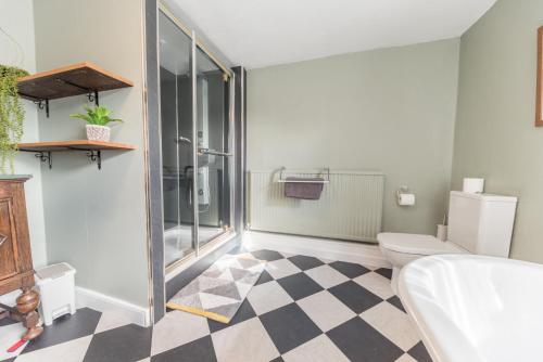 a bathroom with a toilet and a glass shower at Lakeland farmhouse with an acre of gardens, games room and free parking in Rusland