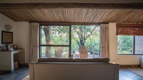 a living room with a couch and a large window at Mashatu Lodge in Lentswelemoriti