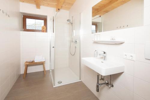 een witte badkamer met een wastafel en een douche bij Hotel Andreas in Alpbach