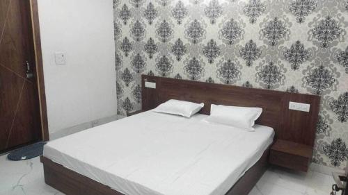1 dormitorio con 1 cama con sábanas blancas y pared en OYO Hotel kadamb, en Palwal