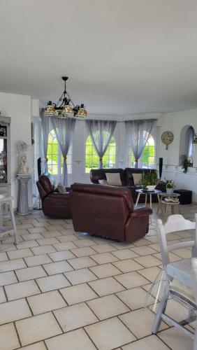 una gran sala de estar con sofás, mesas y ventanas. en Maison d hôtes Salvatrice, en Rouvroy
