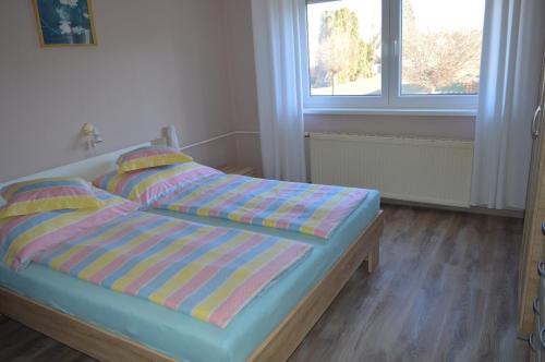 1 dormitorio con cama con sábanas a rayas y ventana en Karolina Appartman en Balatonkeresztúr