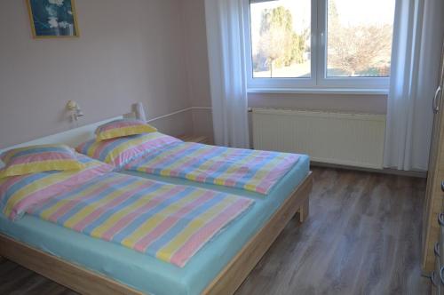 1 dormitorio con cama con sábanas a rayas y ventana en Karolina Appartman, en Balatonkeresztúr
