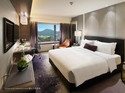 a hotel room with a large white bed and a window at Royal Plaza Hotel in Hong Kong