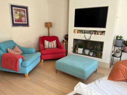 a living room with two chairs and a flat screen tv at Bright, modern & close to historic town in Bishops Waltham