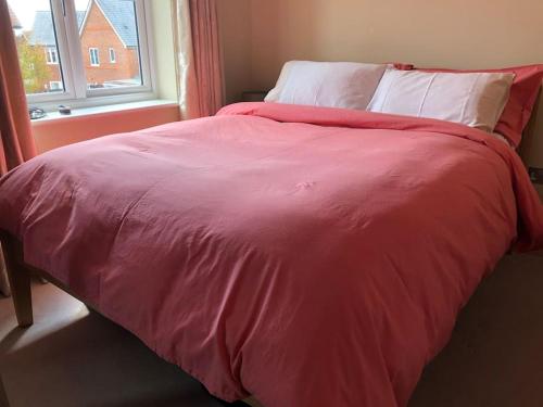 a bed with a red blanket and a window at Bright, modern & close to historic town in Bishops Waltham