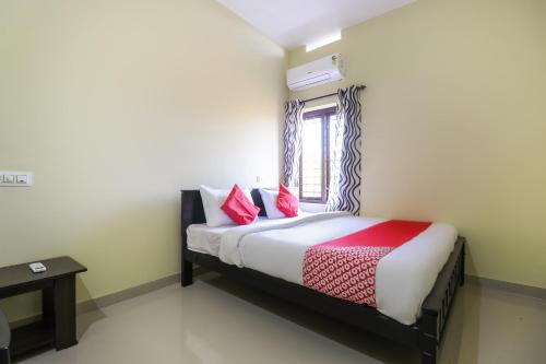 a bedroom with a bed with red pillows and a window at Liberty Apartments in Chakkarakkal