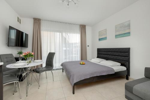 a bedroom with a bed and a table and chairs at White and Grey Studio with Balcony in Międzyzdroje SeaView by Rent like home in Międzyzdroje