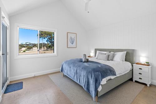 a white bedroom with a bed and a window at Magnolia in Emu Bay
