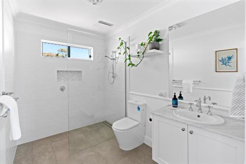 een witte badkamer met een toilet en een wastafel bij Magnolia in Emu Bay