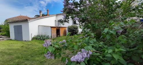 een oud wit huis met een tuin en bloemen bij Jolie villa loc-saisonnière - la petite cocagne in Alleins